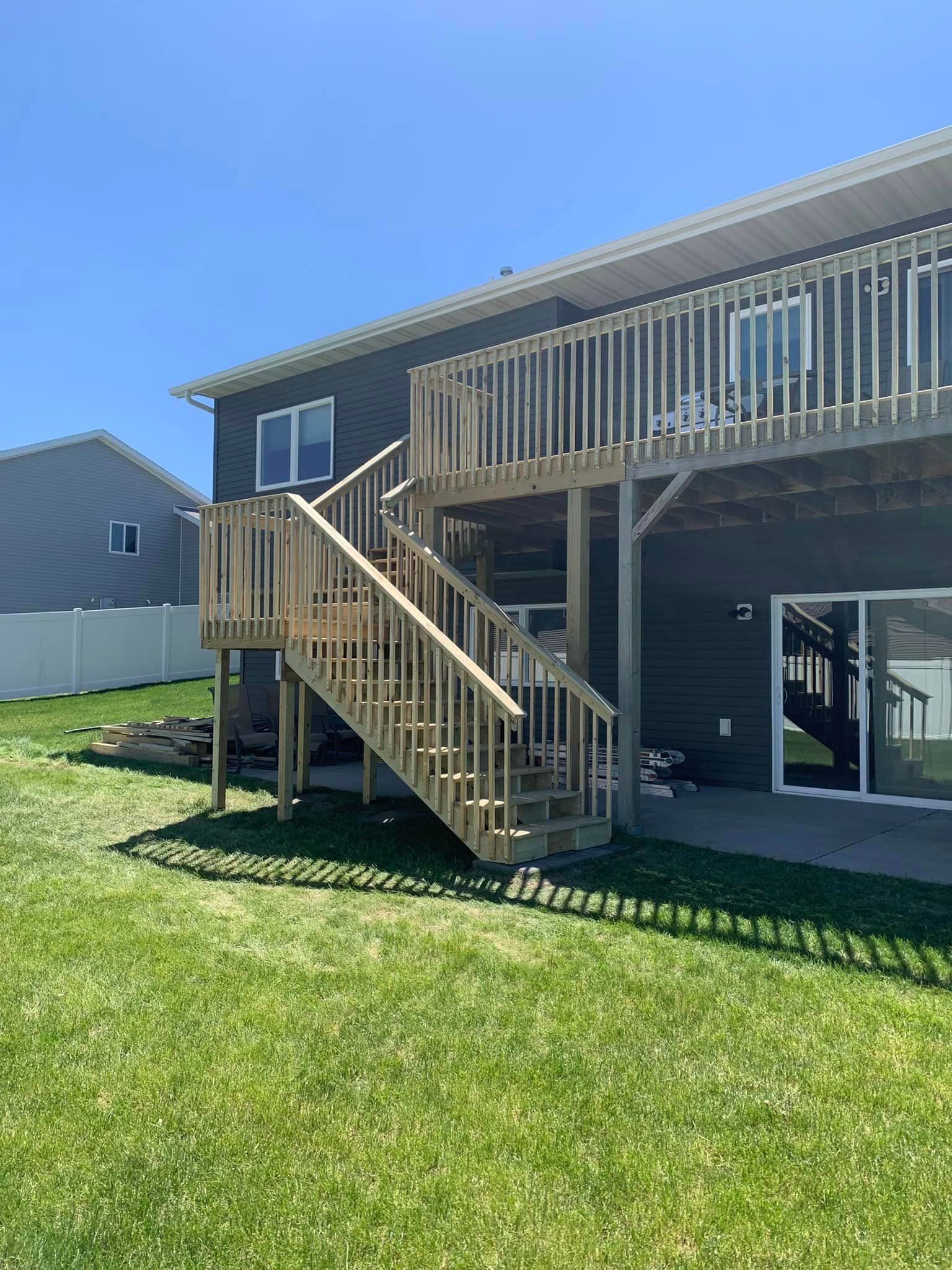 A house with a wooden deck and stairs in the backyard.