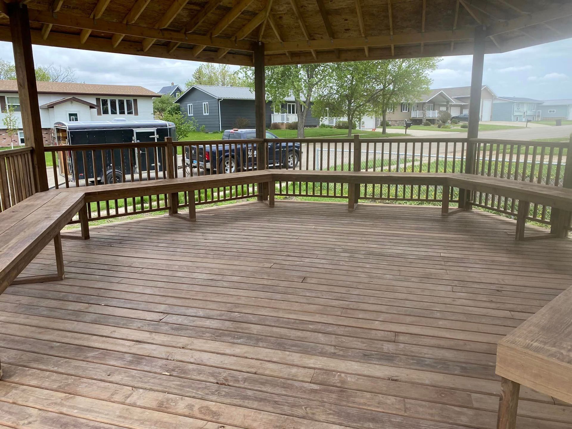 A wooden deck with benches under a gazebo.