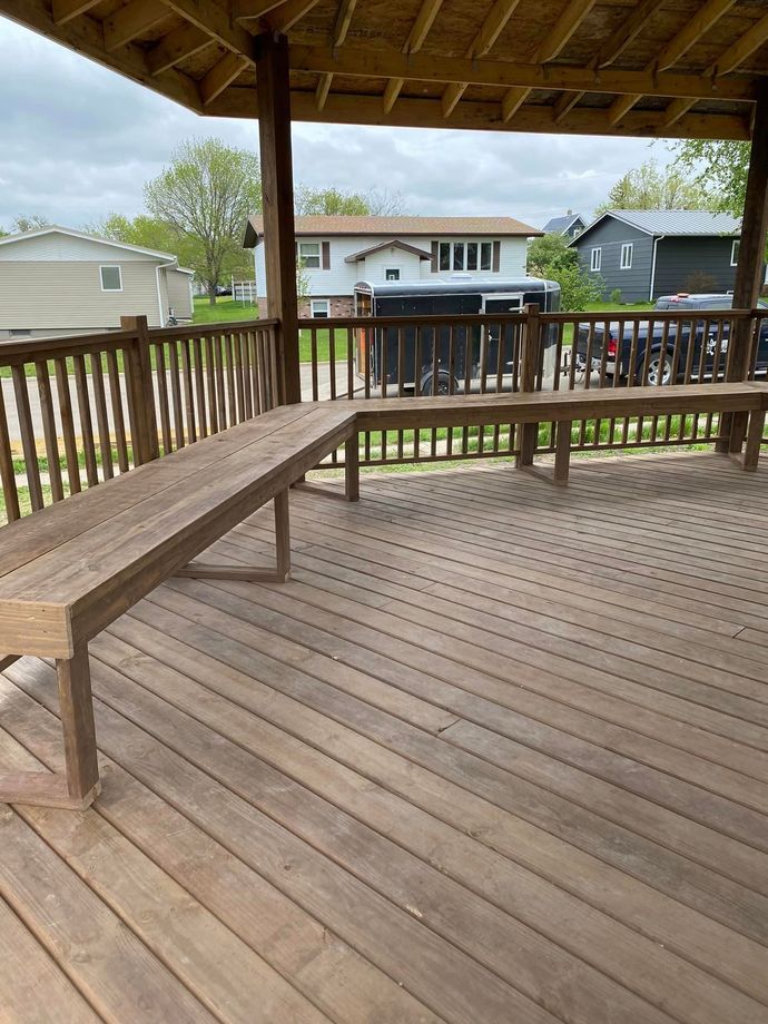 A wooden deck with two benches and a railing.