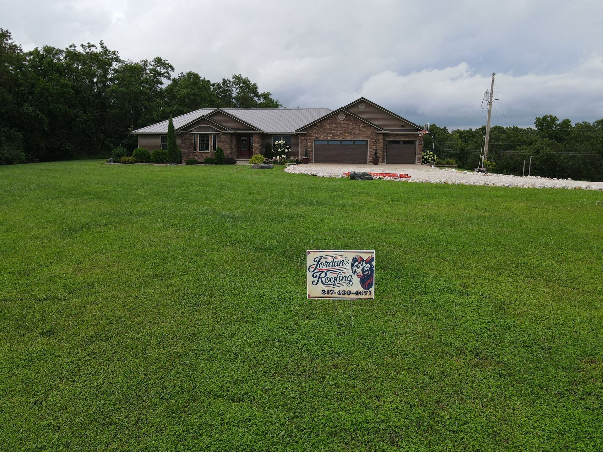 A wide-angle shot of a brick single-story house with a three-car garage, seen across a large, grassy front lawn.