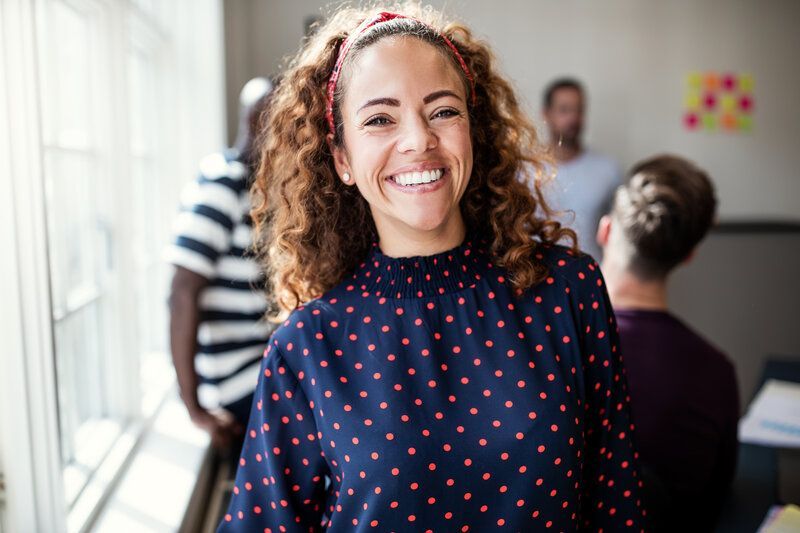 A female career and life coach is smiling in front of a group of people.
