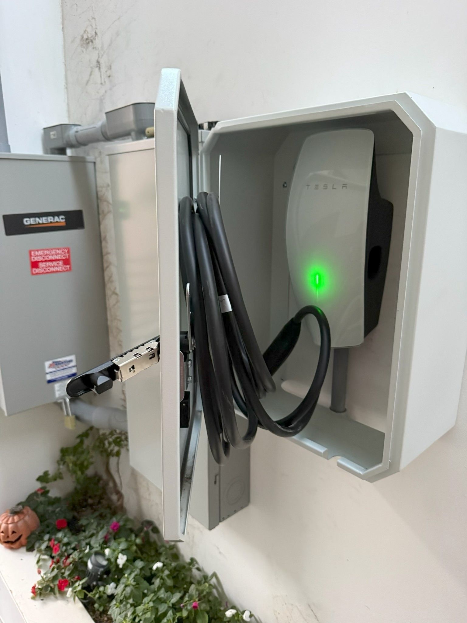 Outdoor EV charging station with open cabinet, cables, and green status light mounted on a wall
