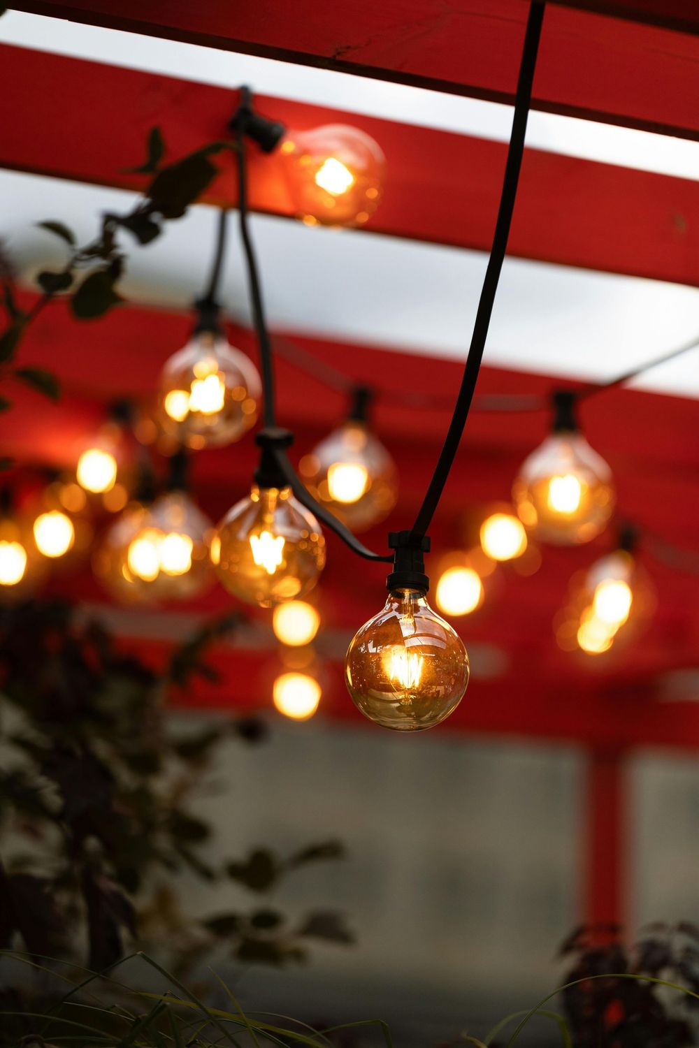 Warm hanging string lights under a red-and-white canopy, softly glowing at night