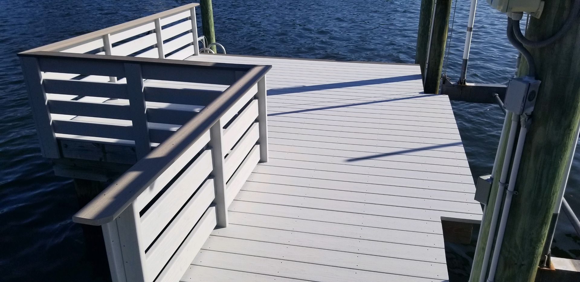 A white dock with a wooden railing overlooking a body of water.