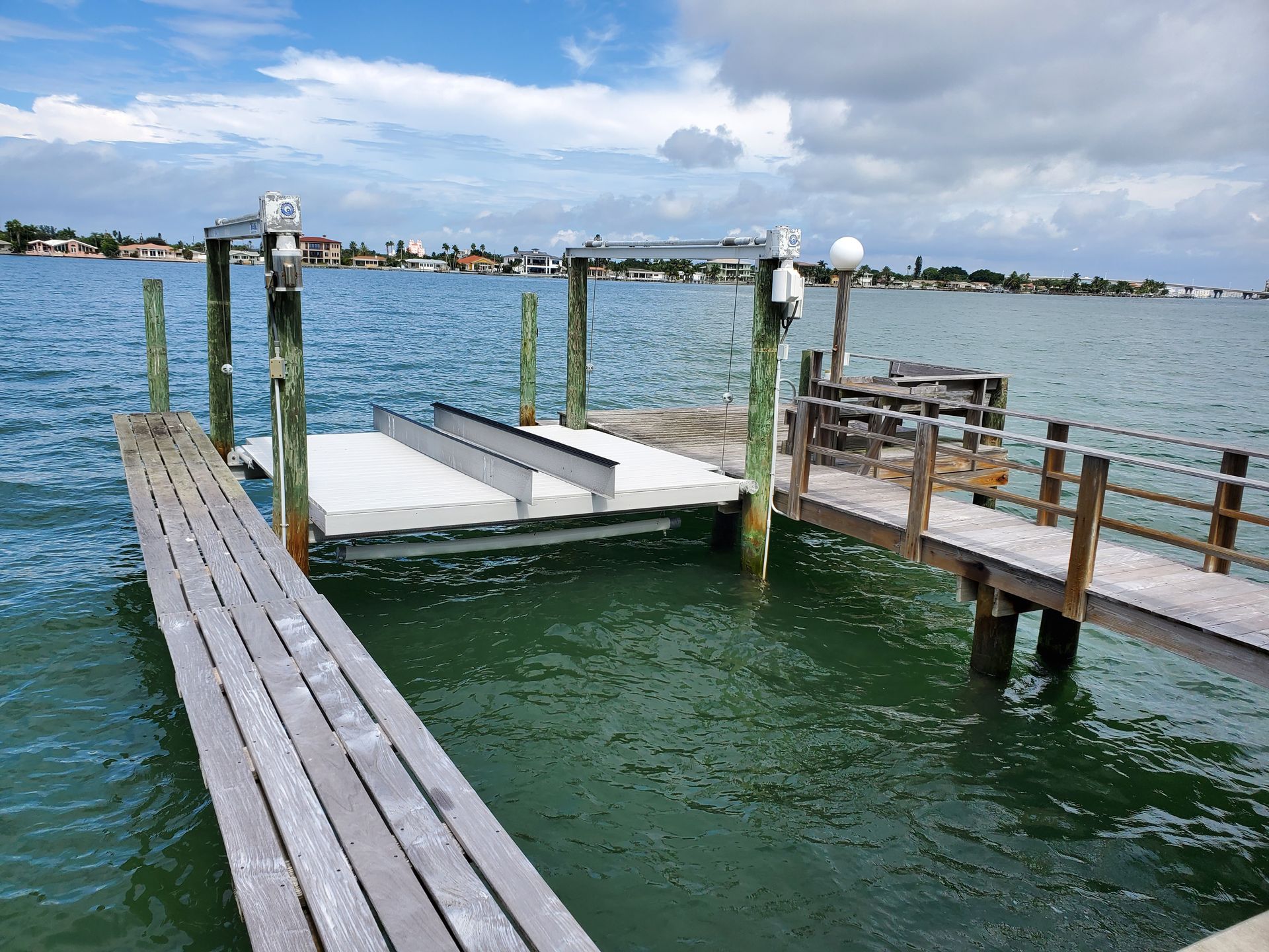 A wooden dock with a lift in the middle of a body of water.