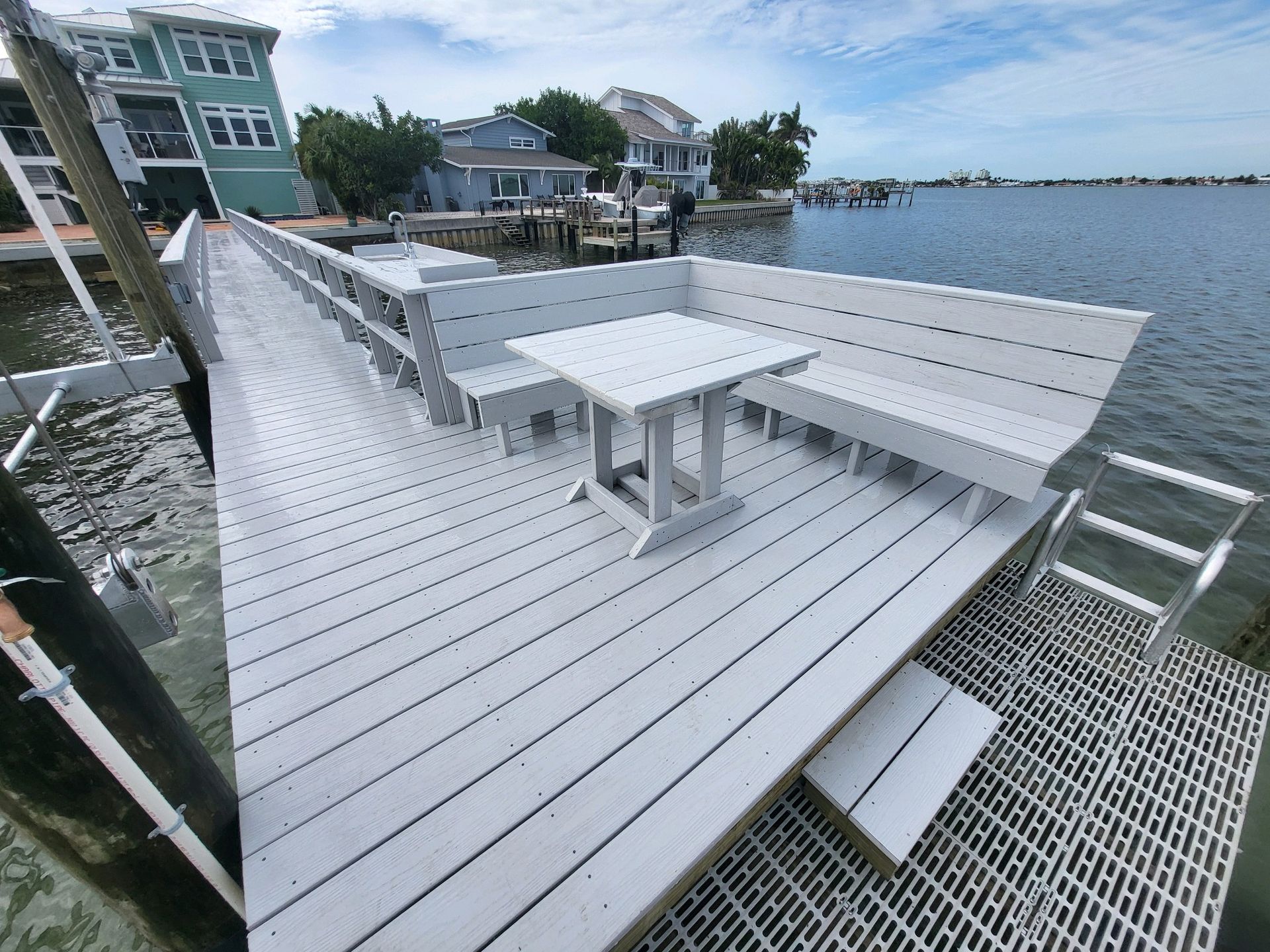 A white dock with a table and benches on it overlooking a body of water.