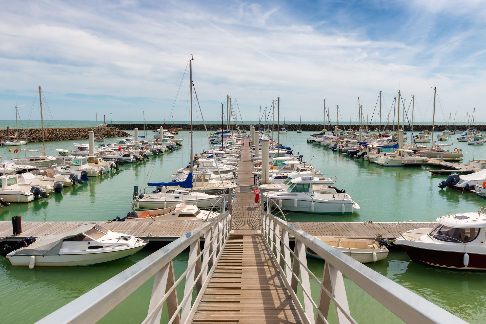 A dock leading to a marina filled with boats at a commercial residence. 