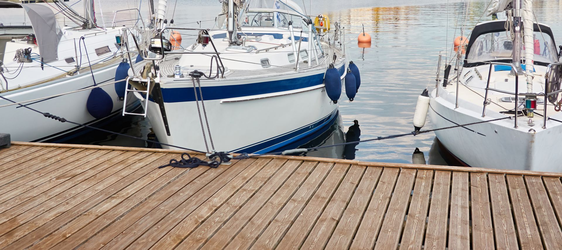 A row of sailboats are docked at a dock.