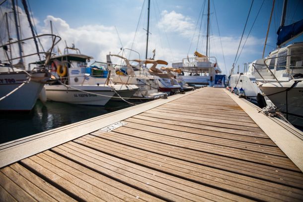 A wooden dock leading to a marina filled with boats.