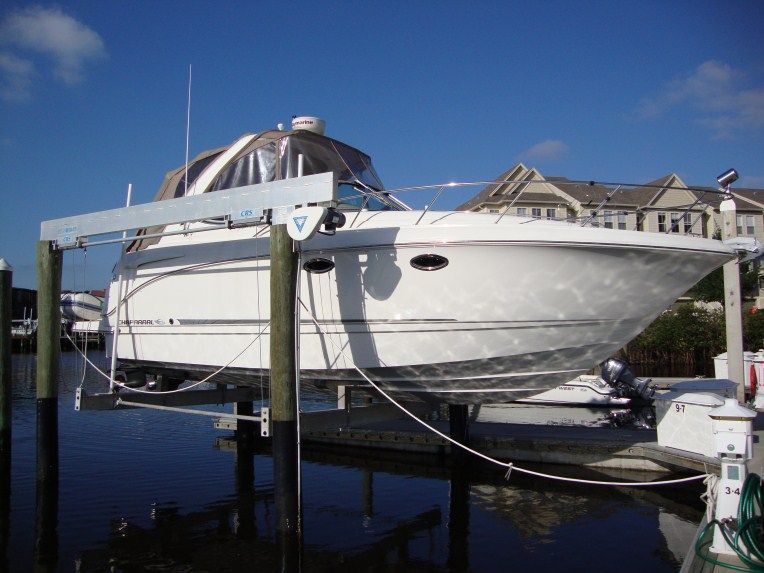 A white boat is sitting on a dock lift in the water.