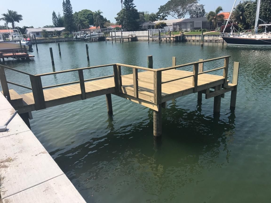 A wooden dock in the middle of a body of water with a boat in the background.