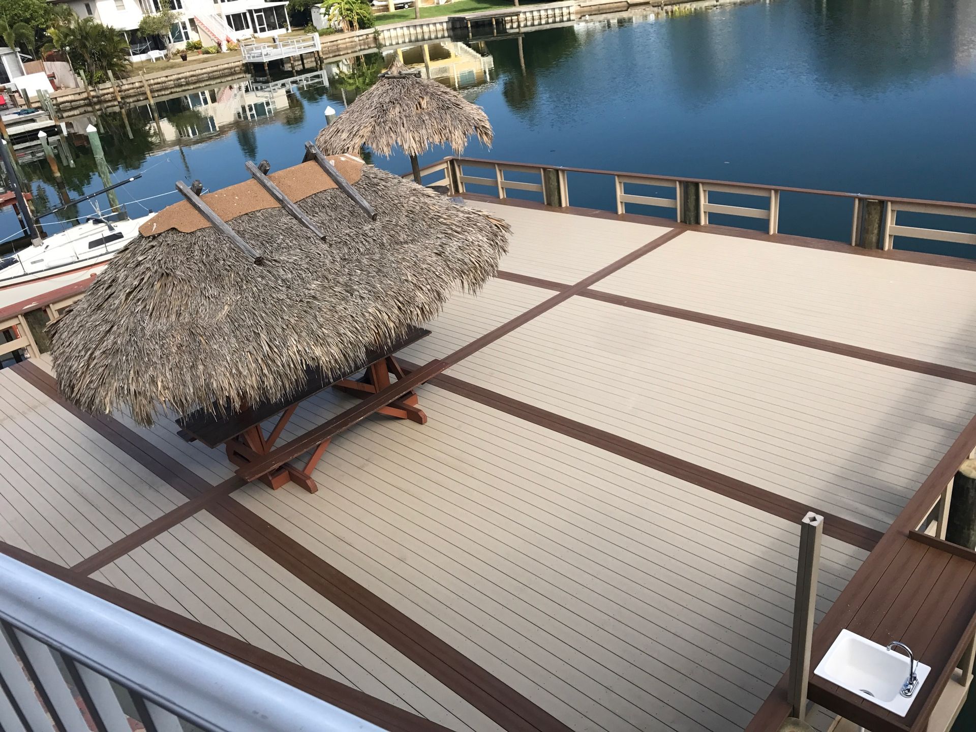 A wooden deck with thatched umbrellas and a table