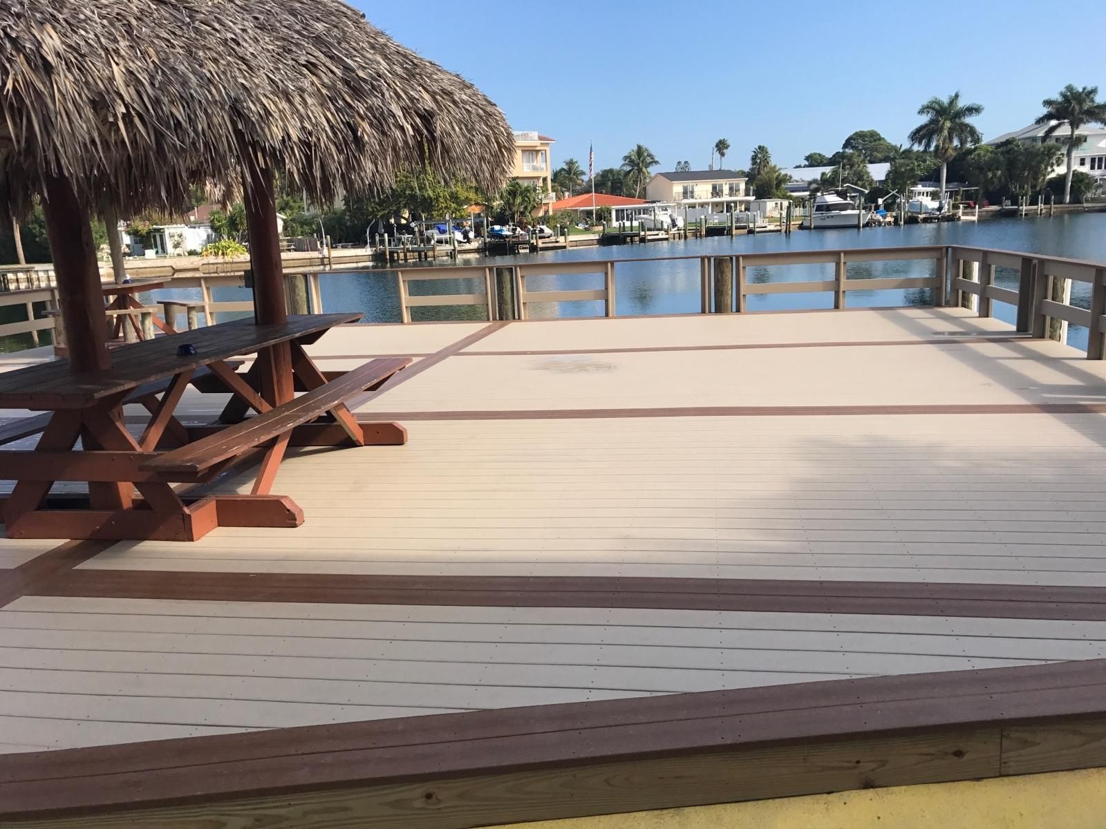 A wooden Dock with a thatched roof and a picnic table.