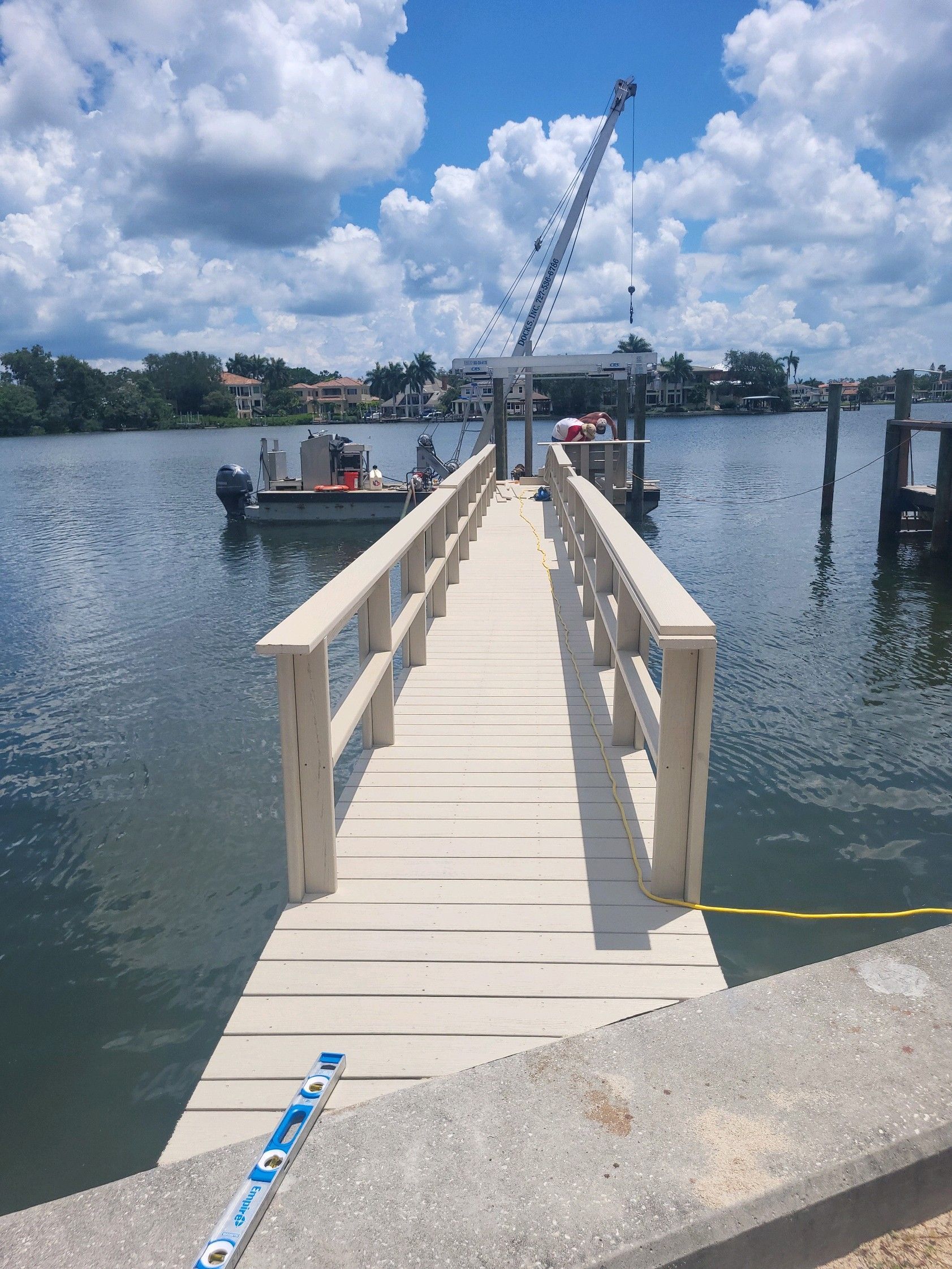 A dock with a boat in the water and a crane in the background