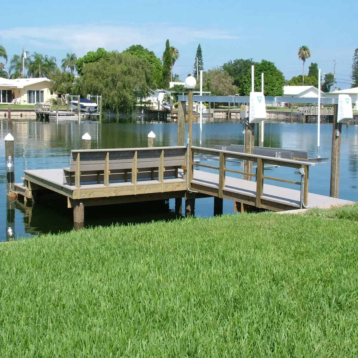 A dock with a bench and a railing overlooking a body of water at a residential home.