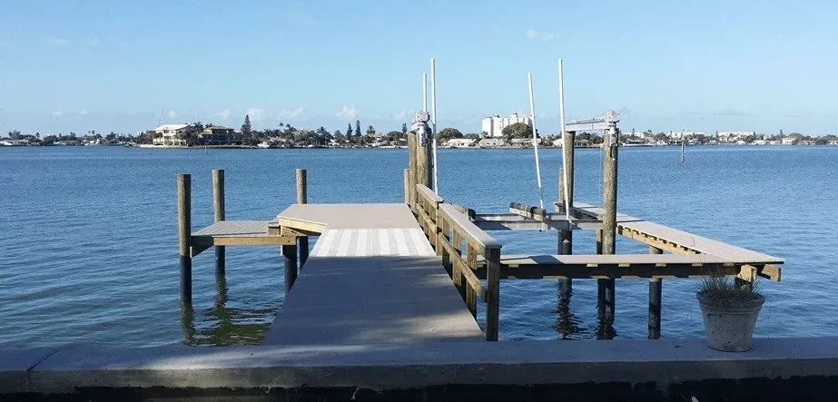 A dock in the middle of a body of water with a city in the background.