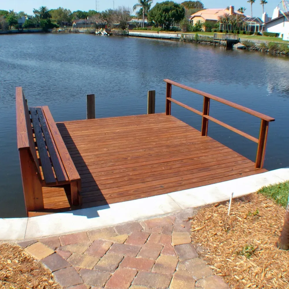 A Wood dock with a bench and railing overlooking a body of water.