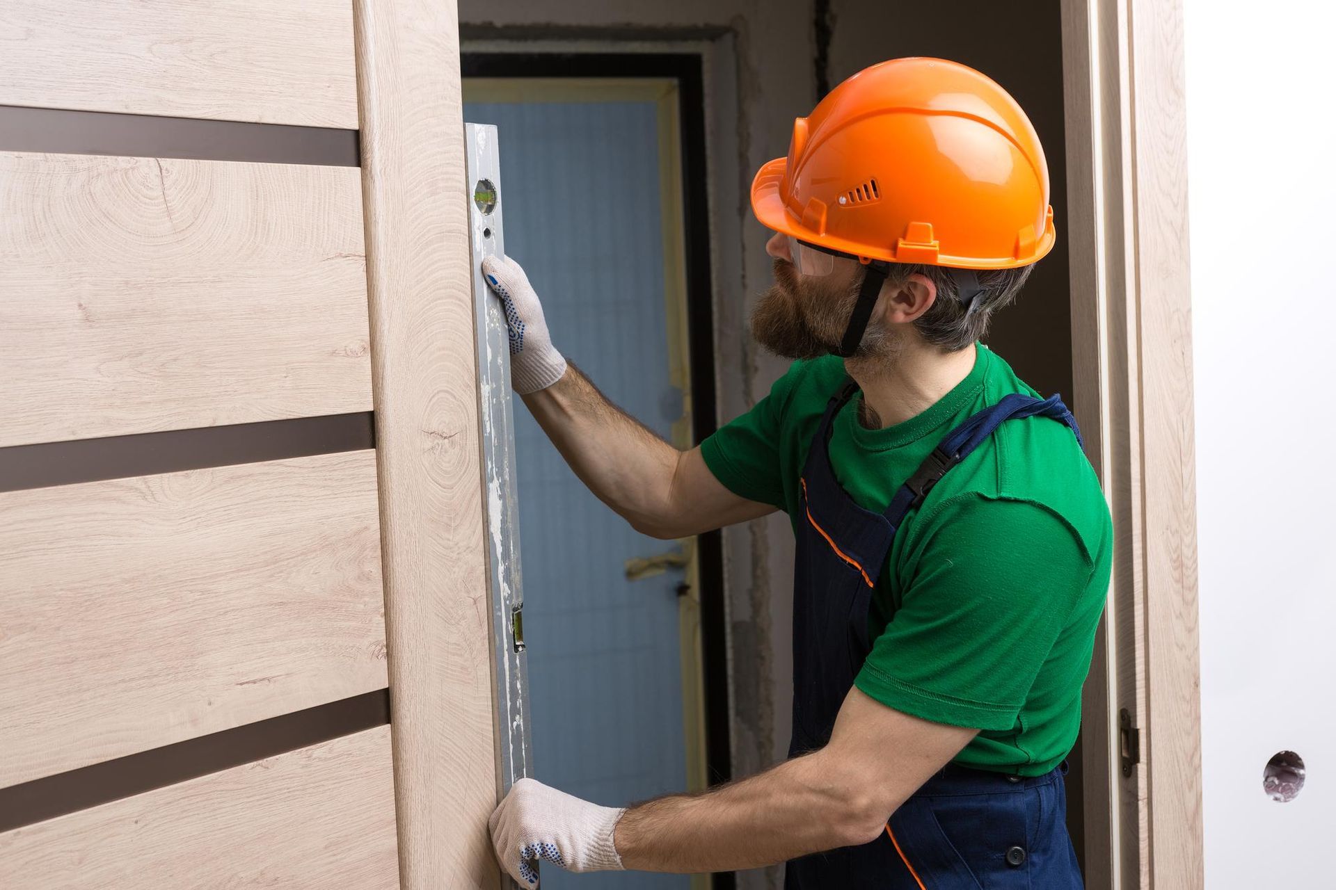 a man in a hard hat is measuring a door with a level