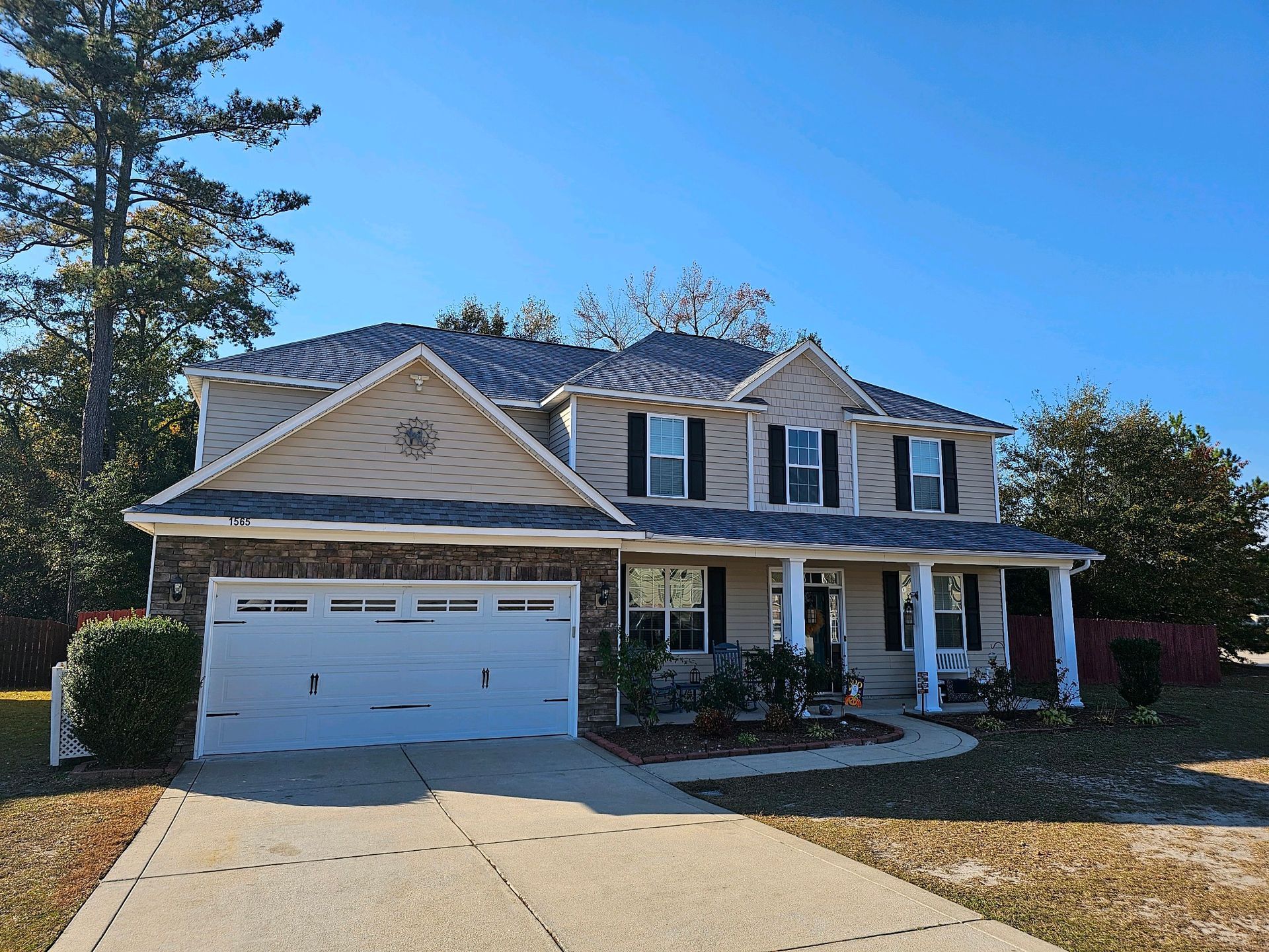A large house with a white garage door and a large porch.