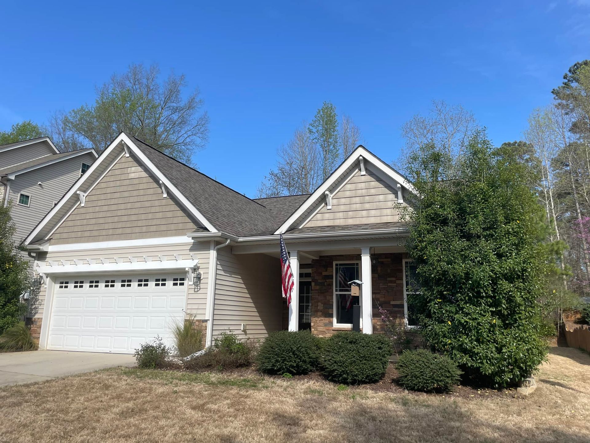 A house with a large garage and a flag on the front porch.