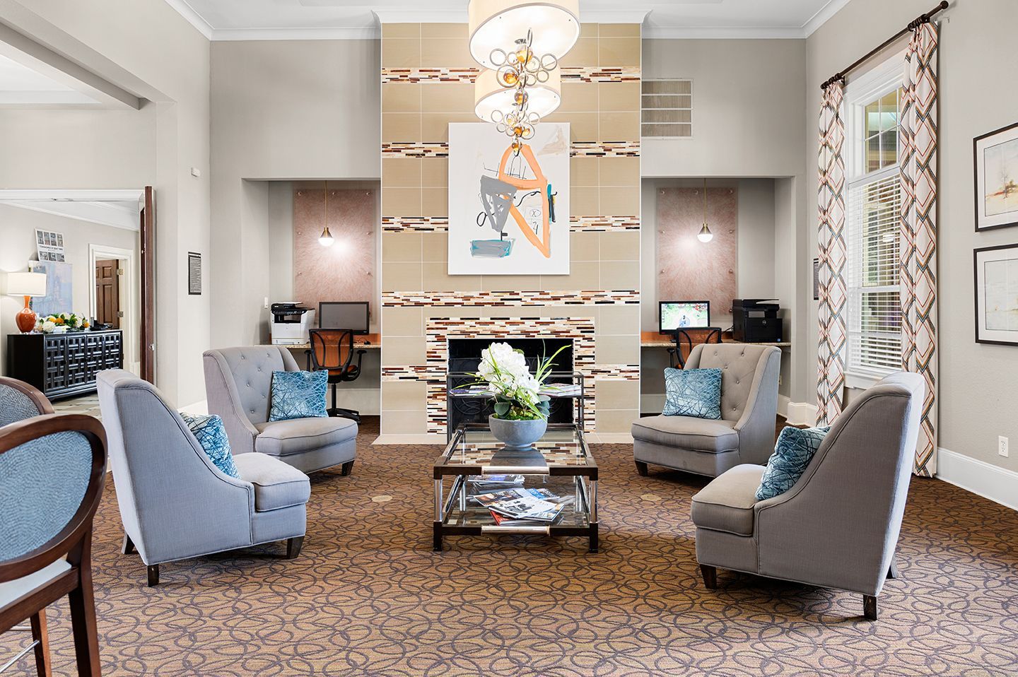 Cozy lobby with armchairs, fireplace, artwork, computers, and a chandelier at Townhomes of Bent Tree, offers apartments for rent in Dallas, TX.