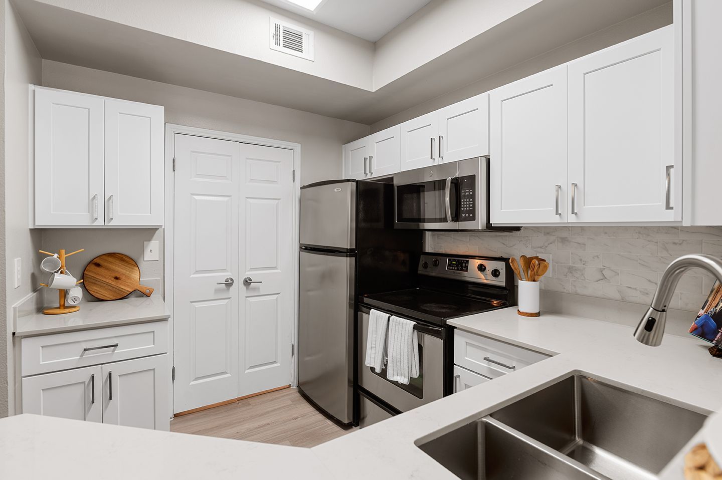 White kitchen with stainless steel appliances and light countertops at Townhomes of Bent Tree, offers apartments in North Dallas, TX.