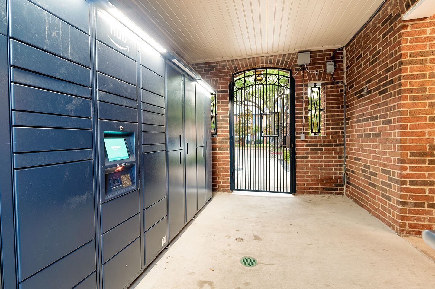 Blue package lockers in a brick alcove, leading to a gated exterior at Townhomes of Bent Tree, offers pet-friendly apartments in Plano ISD.