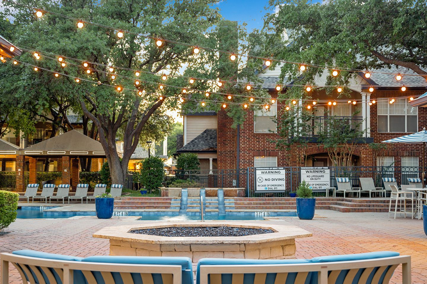 Courtyard with pool, fire pit, seating, and strung lights at an apartment complex at Townhomes of Bent Tree,  in Far North Dallas.