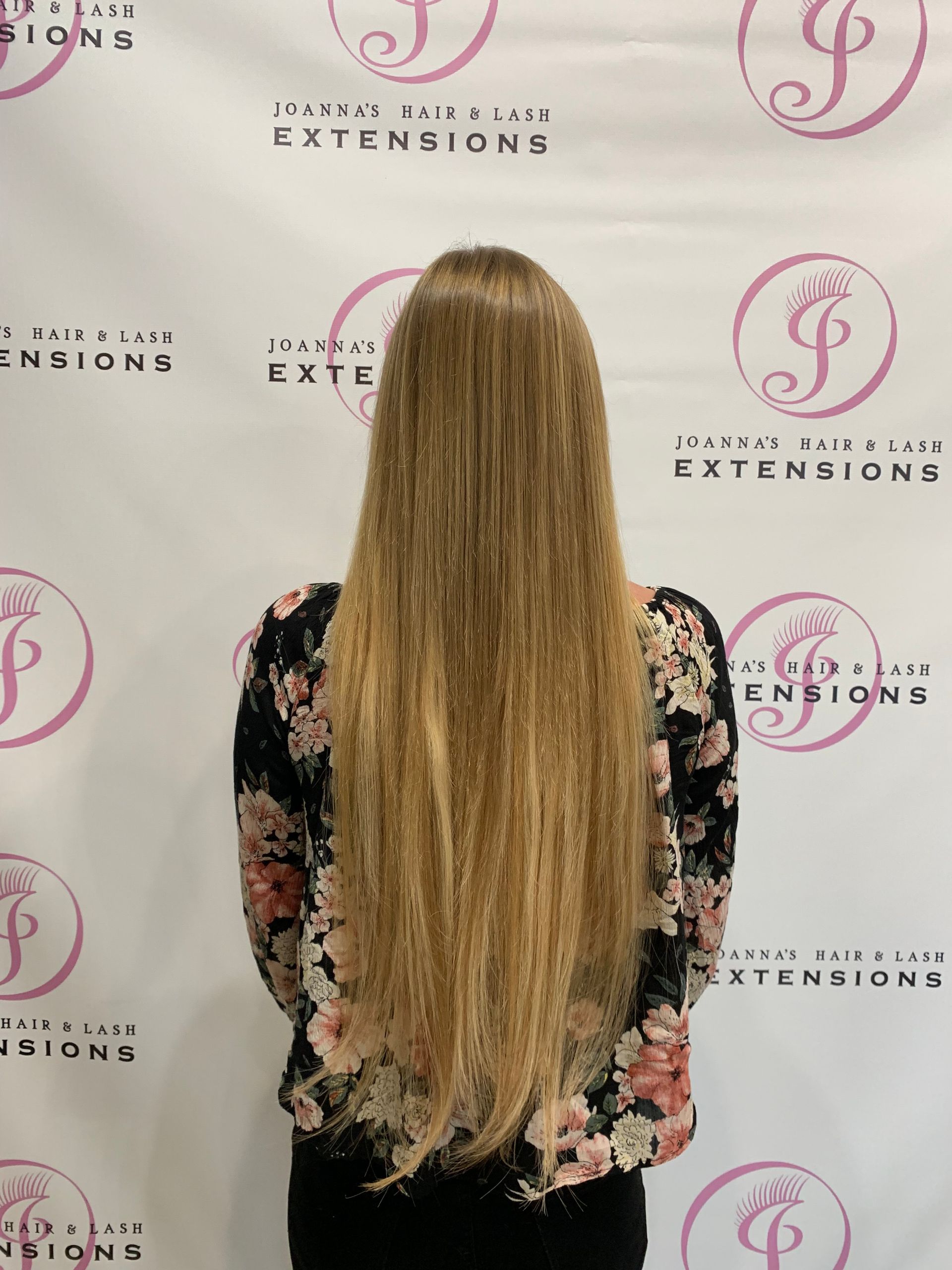 a woman with long blonde hair is standing in front of a sign that says extensions
