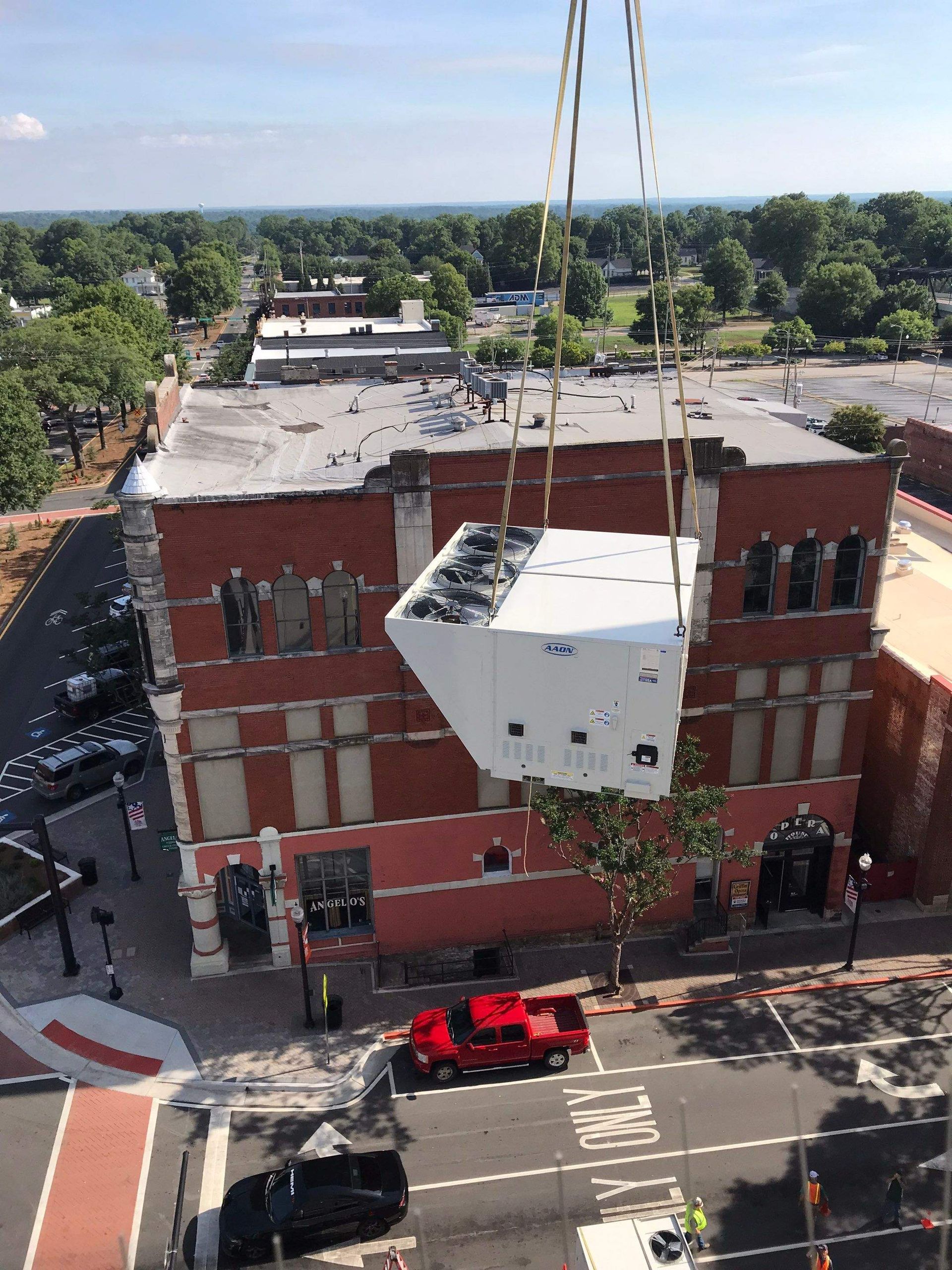 A large white box is being lifted into the air by a crane.