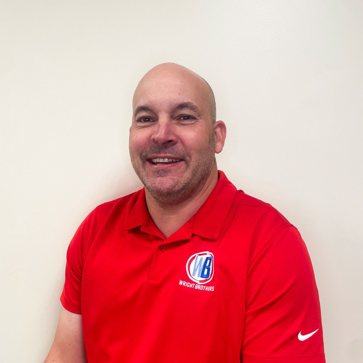 A man wearing a red nike shirt is smiling for the camera