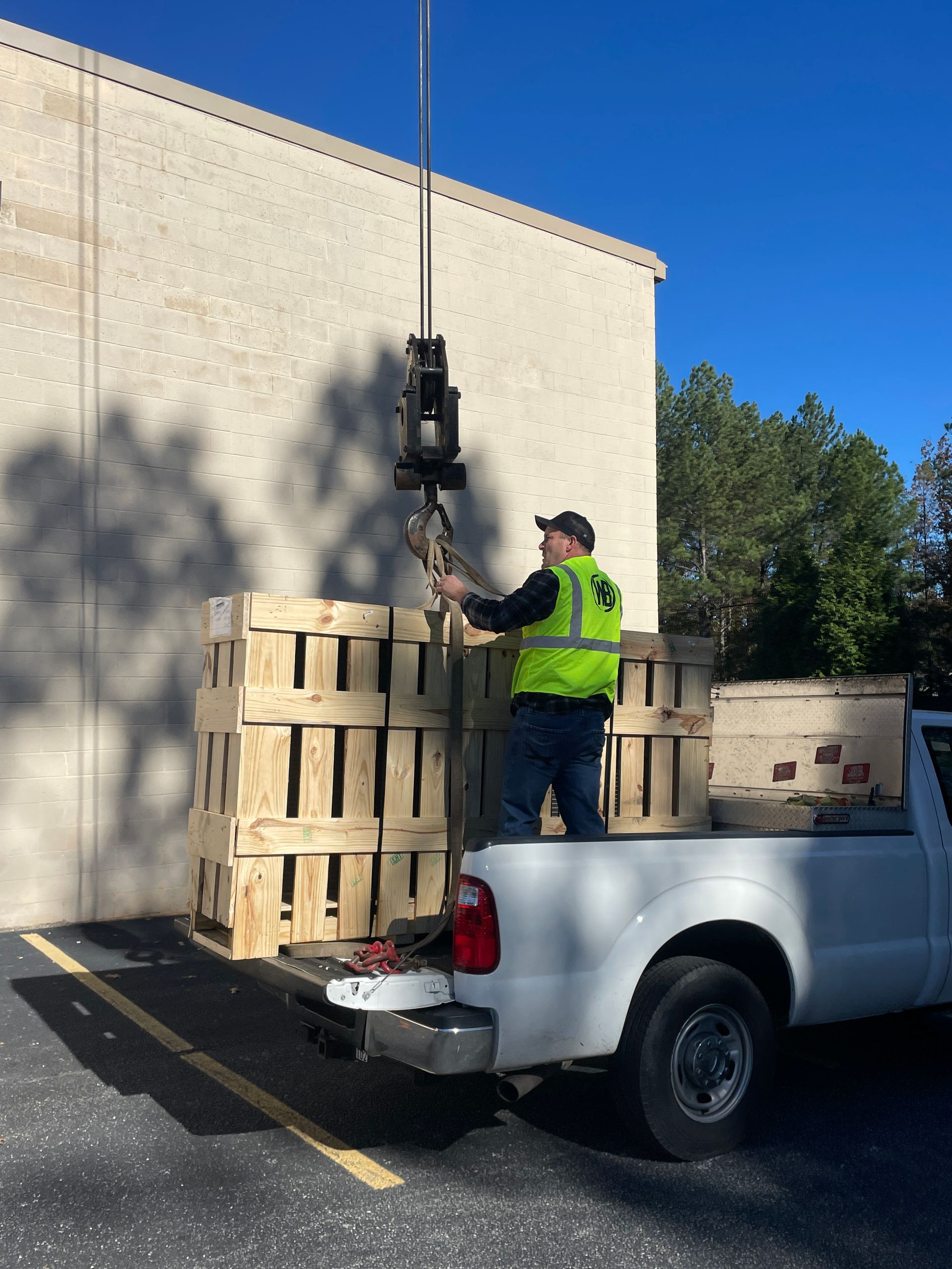 A man and a woman are standing in a living room with a dog and a remote control.