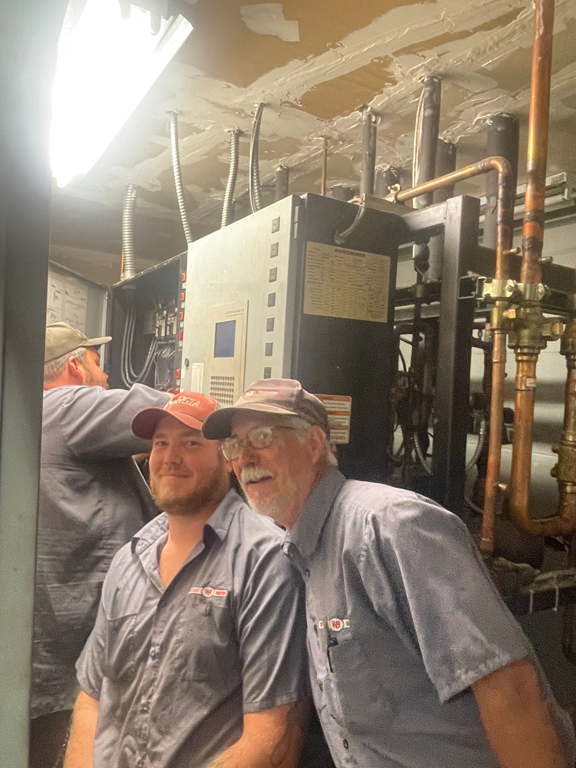 Two men are standing next to each other in front of a machine.