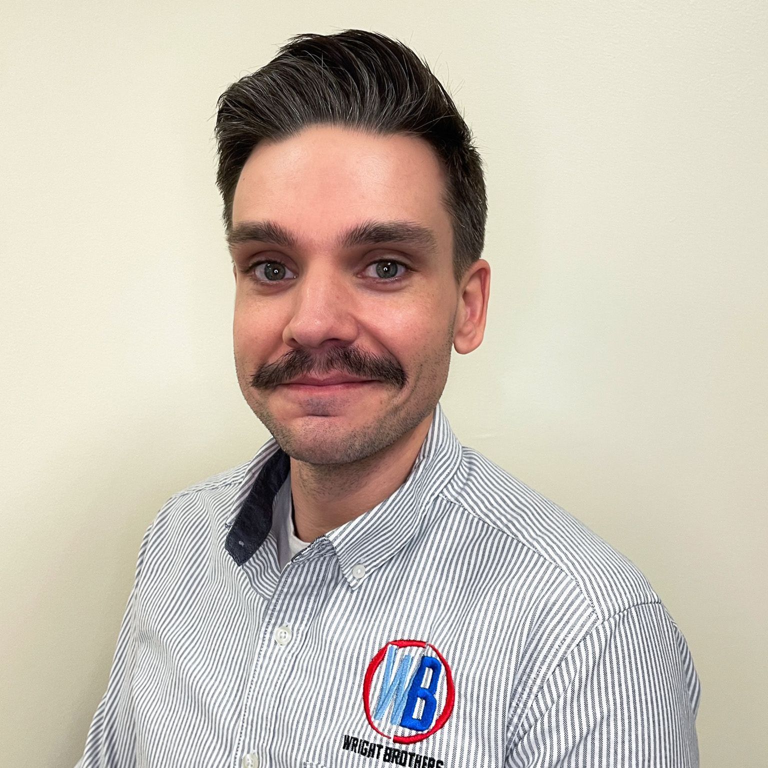 A man with a mustache is wearing a striped shirt.