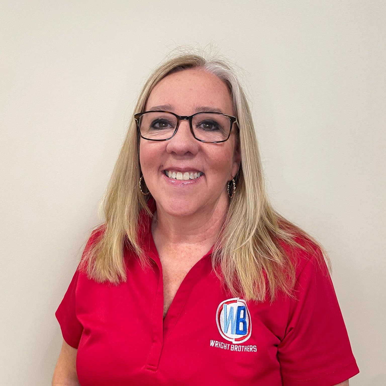 A woman wearing glasses and a red shirt is smiling for the camera.