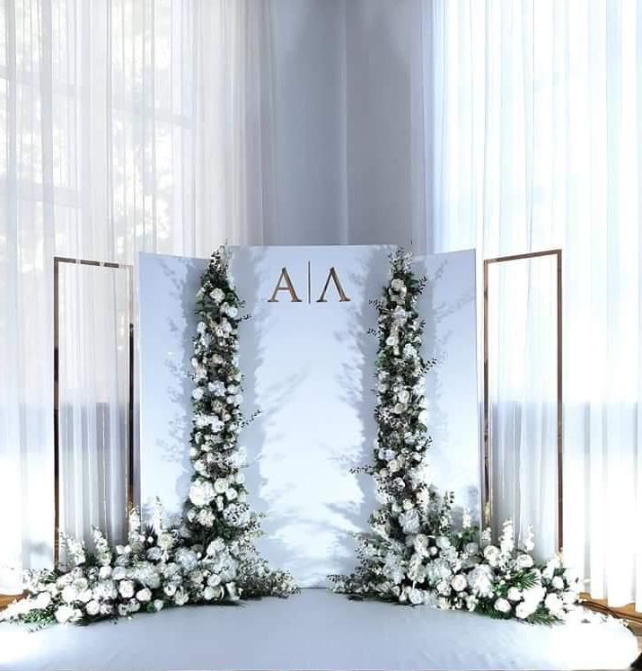 A white wall with the letters a and a on it is surrounded by white flowers.