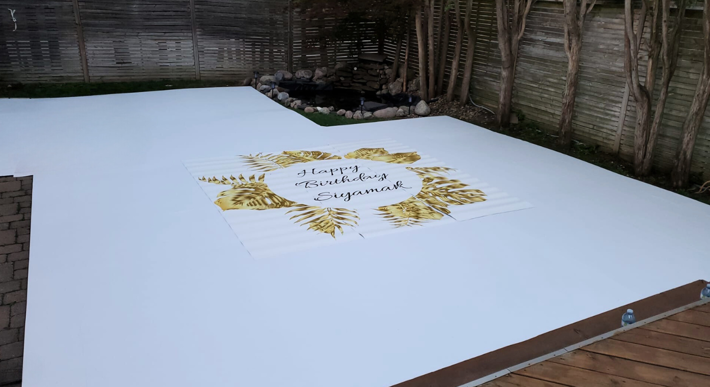 A white carpet with a gold logo on it is sitting on top of a wooden floor.