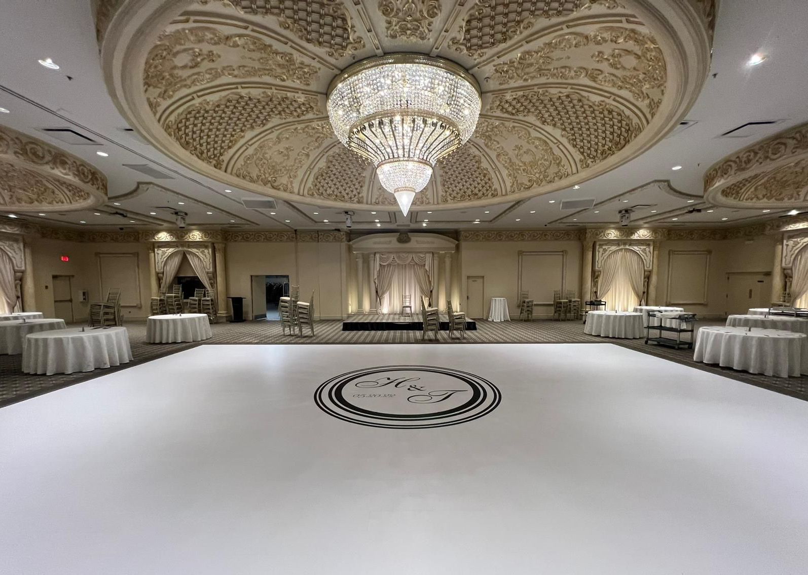 A large ballroom with a white dance floor and a chandelier.