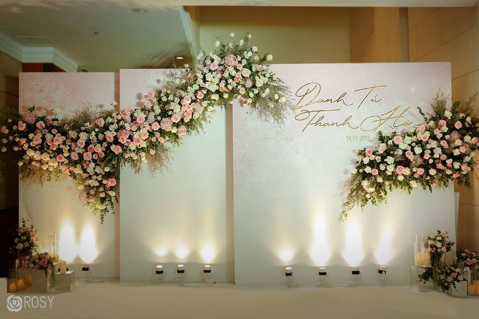 A wall decorated with flowers and candles for a wedding reception.