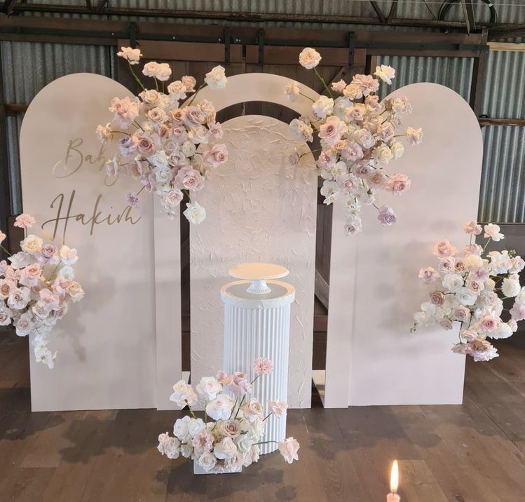 A table with flowers and candles in front of a wall.