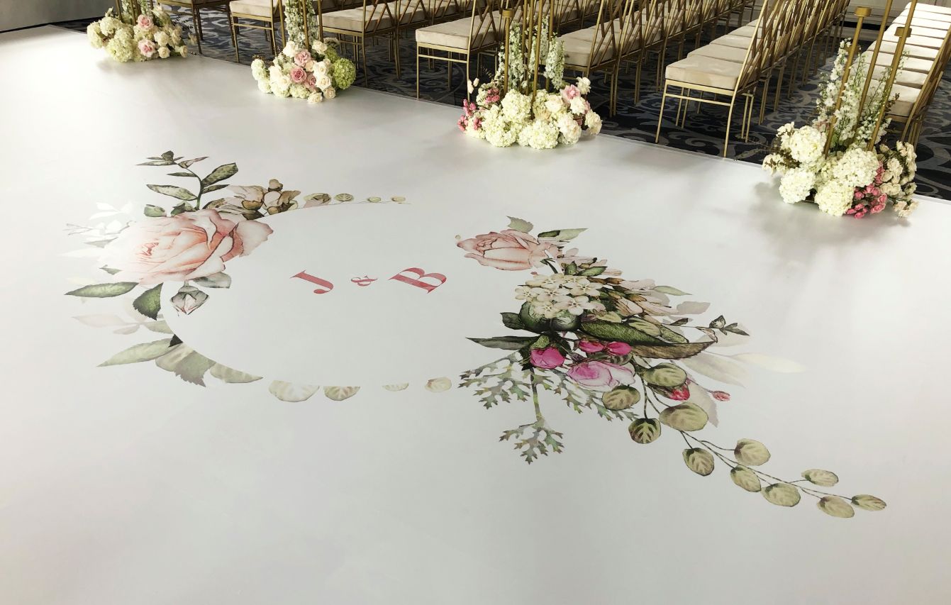 A wedding ceremony is taking place on a white floor with a floral design on it.