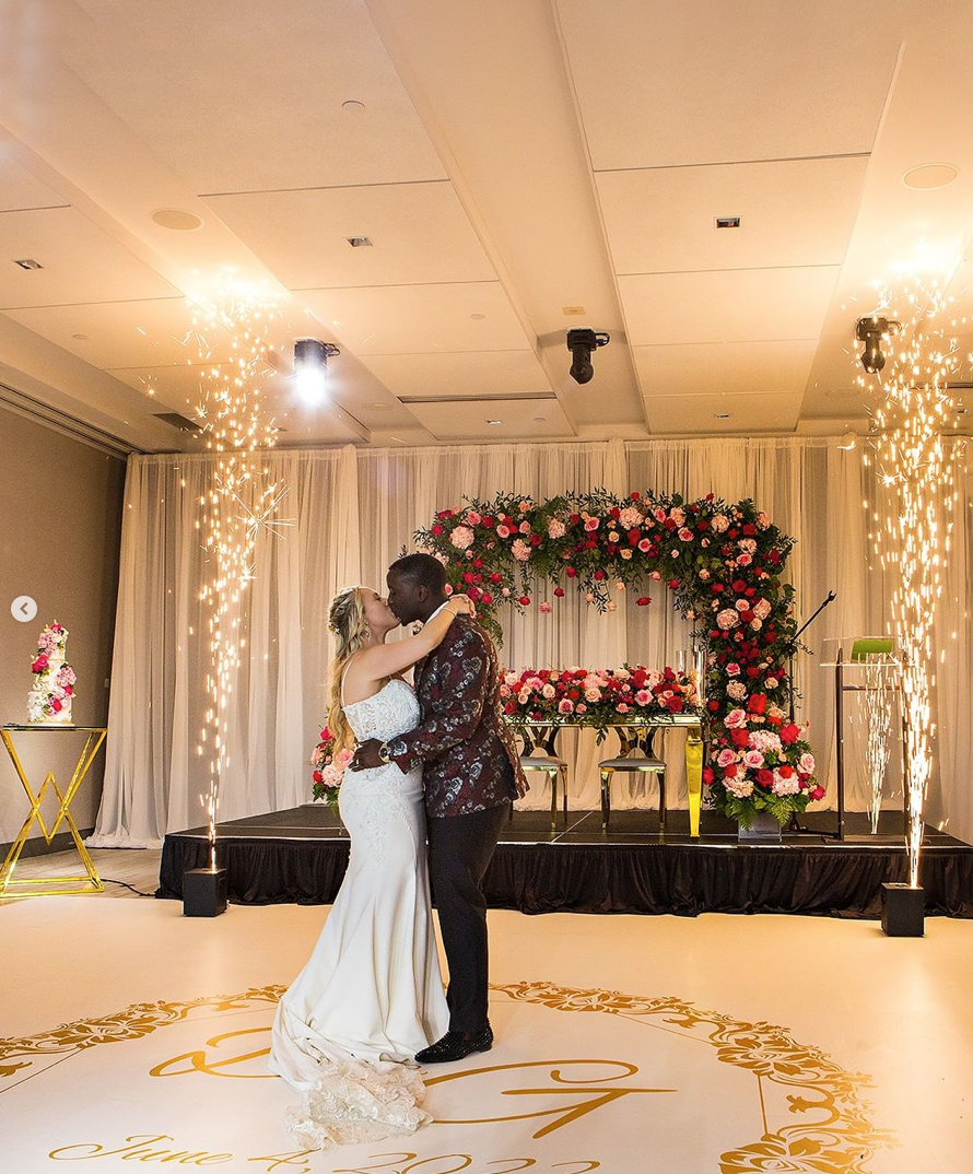 A bride and groom are kissing on a dance floor at their wedding reception.