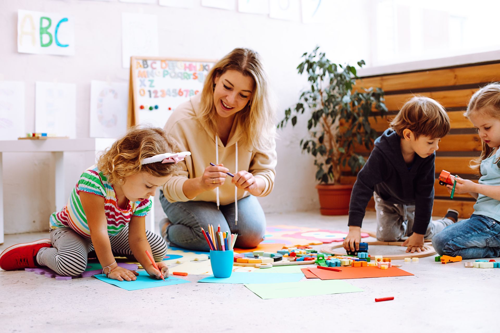 A group of people are sitting on the floor playing with a robot.