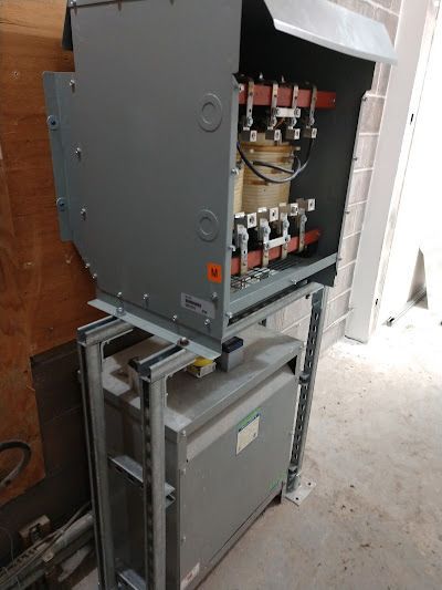 Electrical transformer equipment, grey metal, mounted on metal frame.