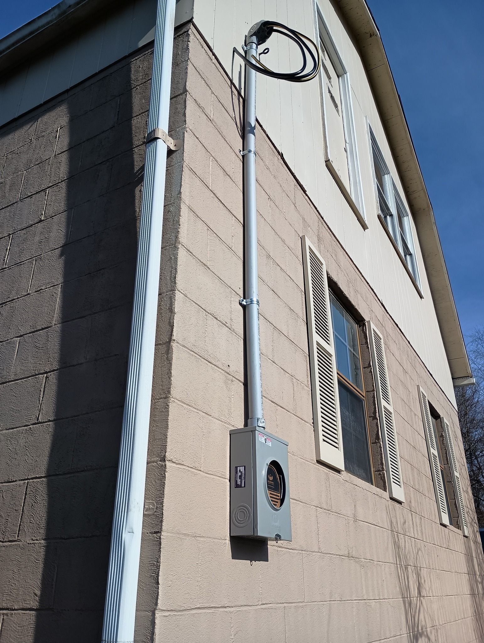 Electrical meter and conduit on the stucco exterior of a two-story building.
