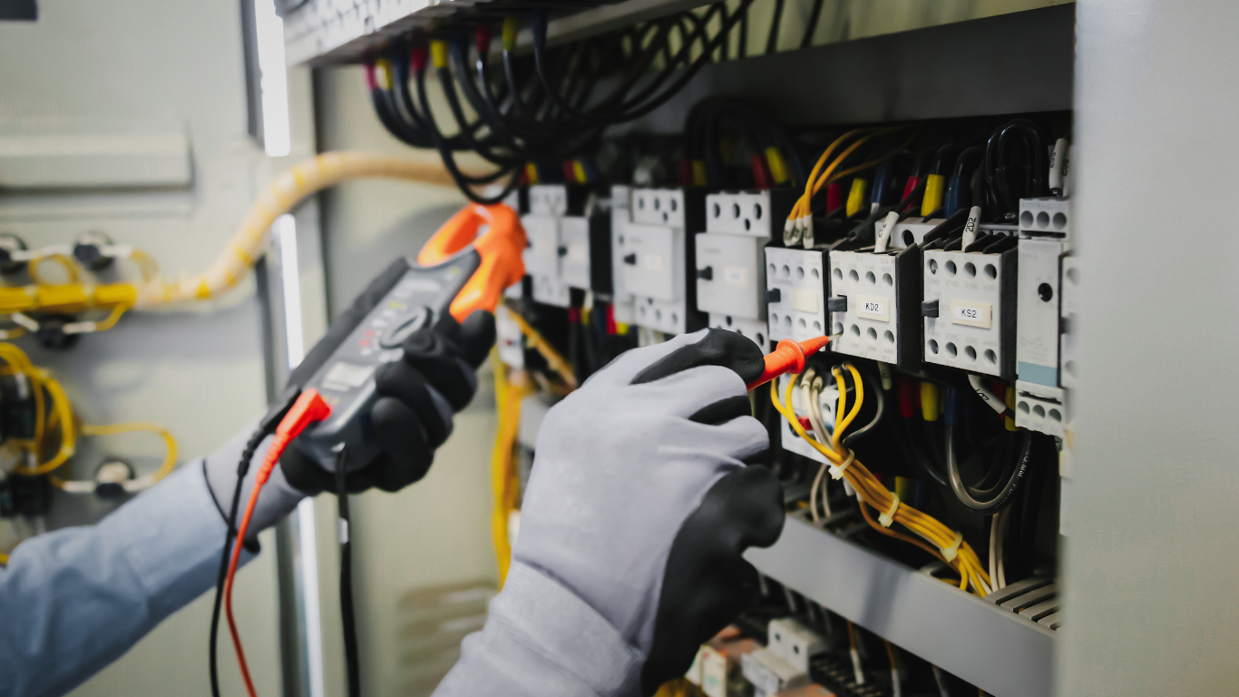 Electrician using a multimeter to test wiring inside an electrical panel.