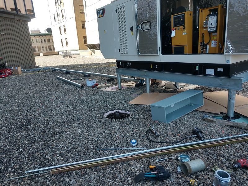 Generator on a rooftop with open door, surrounded by tools and equipment.