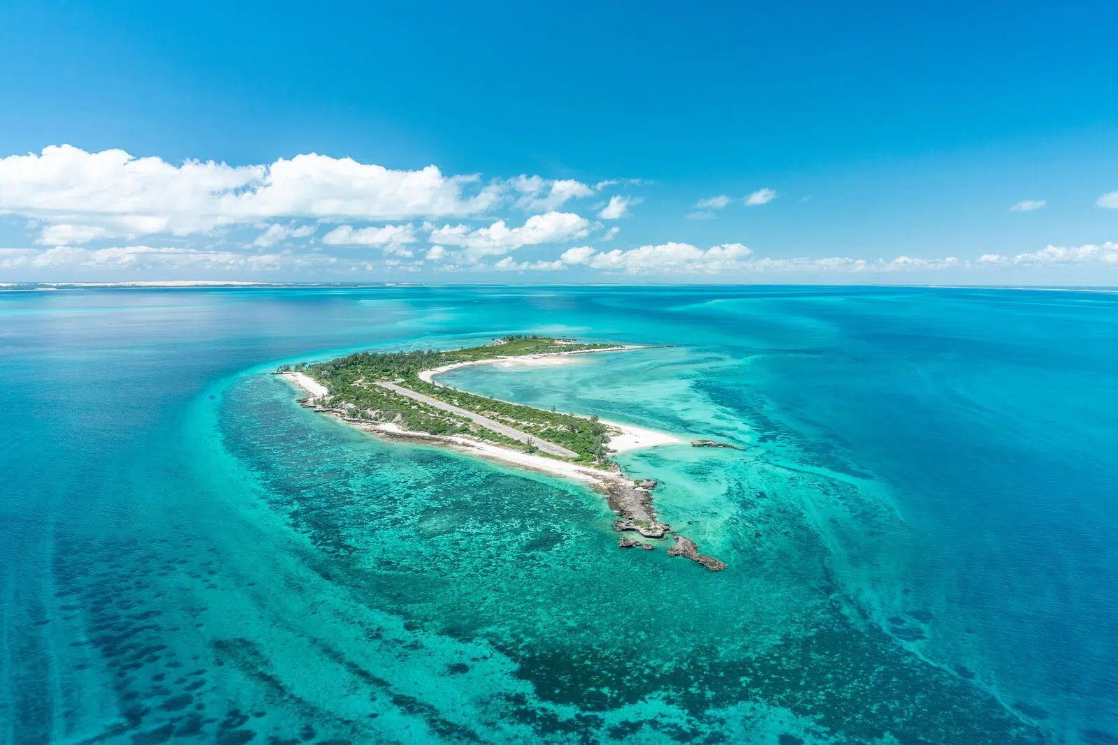 Aerial view of a small tropical island surrounded by bright turquoise ocean and coral reefs