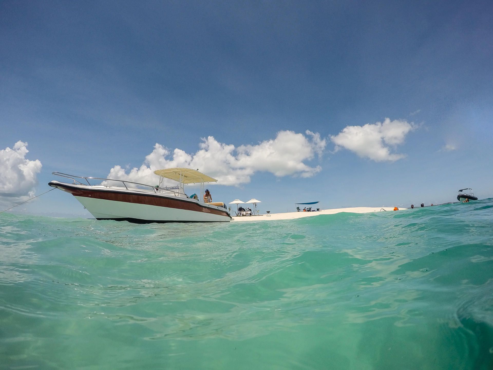 Speedboat on turquoise water near a sandy beach under a blue sky