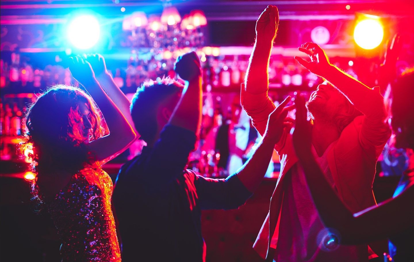 People dancing in a club under bright pink and blue stage lights